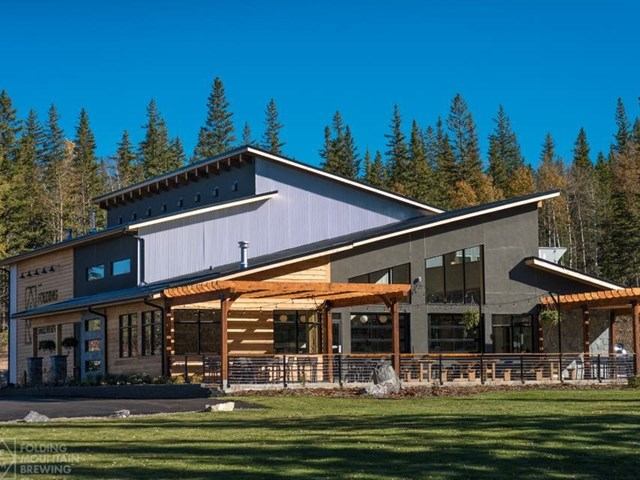 Modern taproom with outdoor seating, large windows, and scenic mountain surroundings.