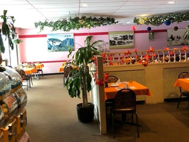Restaurant interior includes dining tables, decorative greenery, wall art, and spacious seating areas.