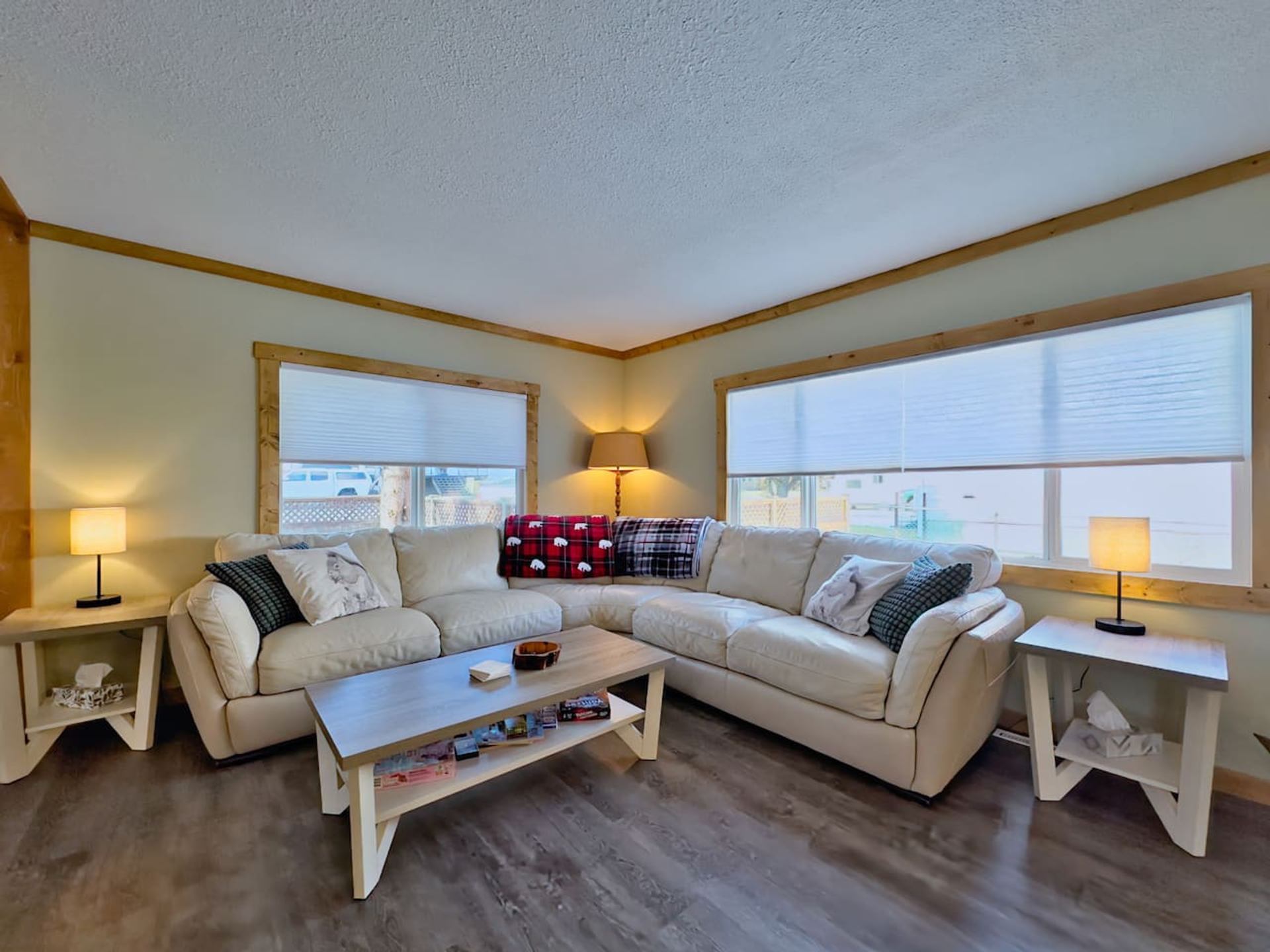A cozy living room with a beige L-shaped sectional sofa, coffee table, and lamps.