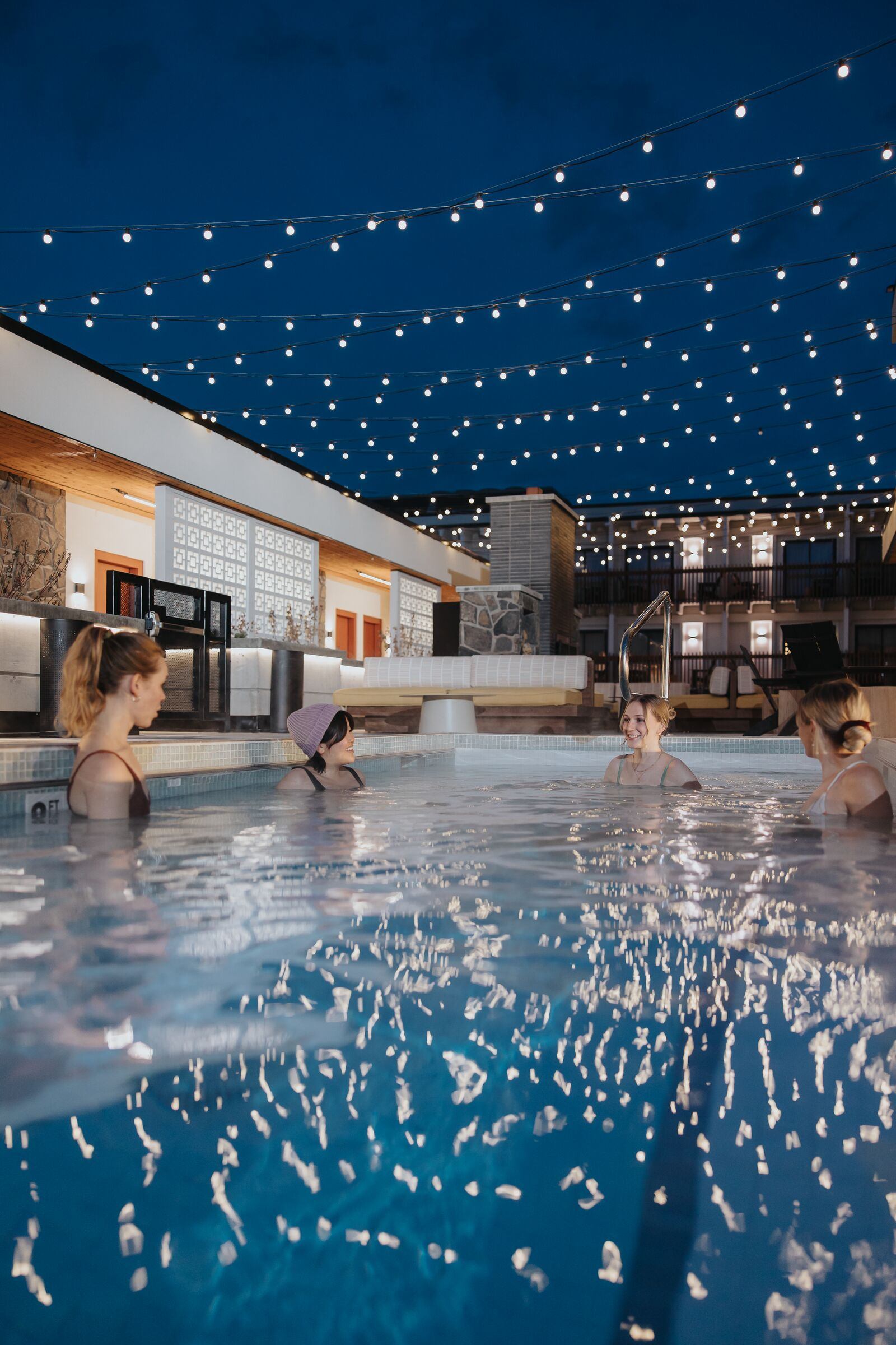 Four friends enjoying the outdoor pool at Moxy Hotel in Banff.