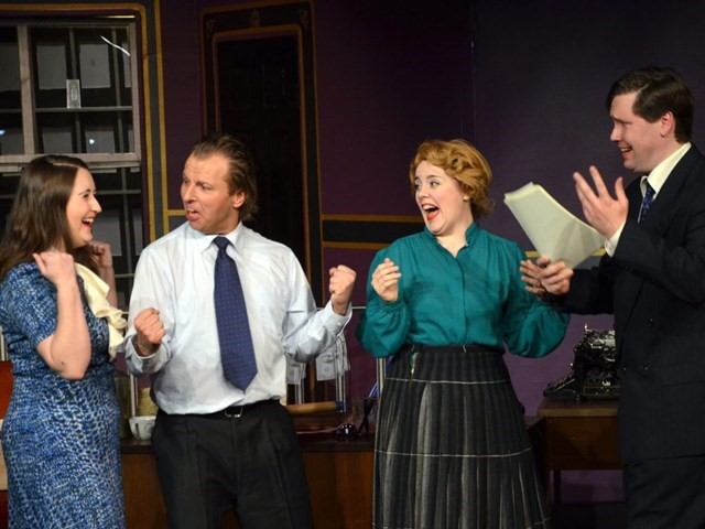 Actors in period costumes read scripts on a theatre stage with a wood podium.