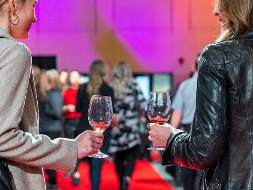 Two people holding wine glasses on a red carpet at Winefest Edmonton.