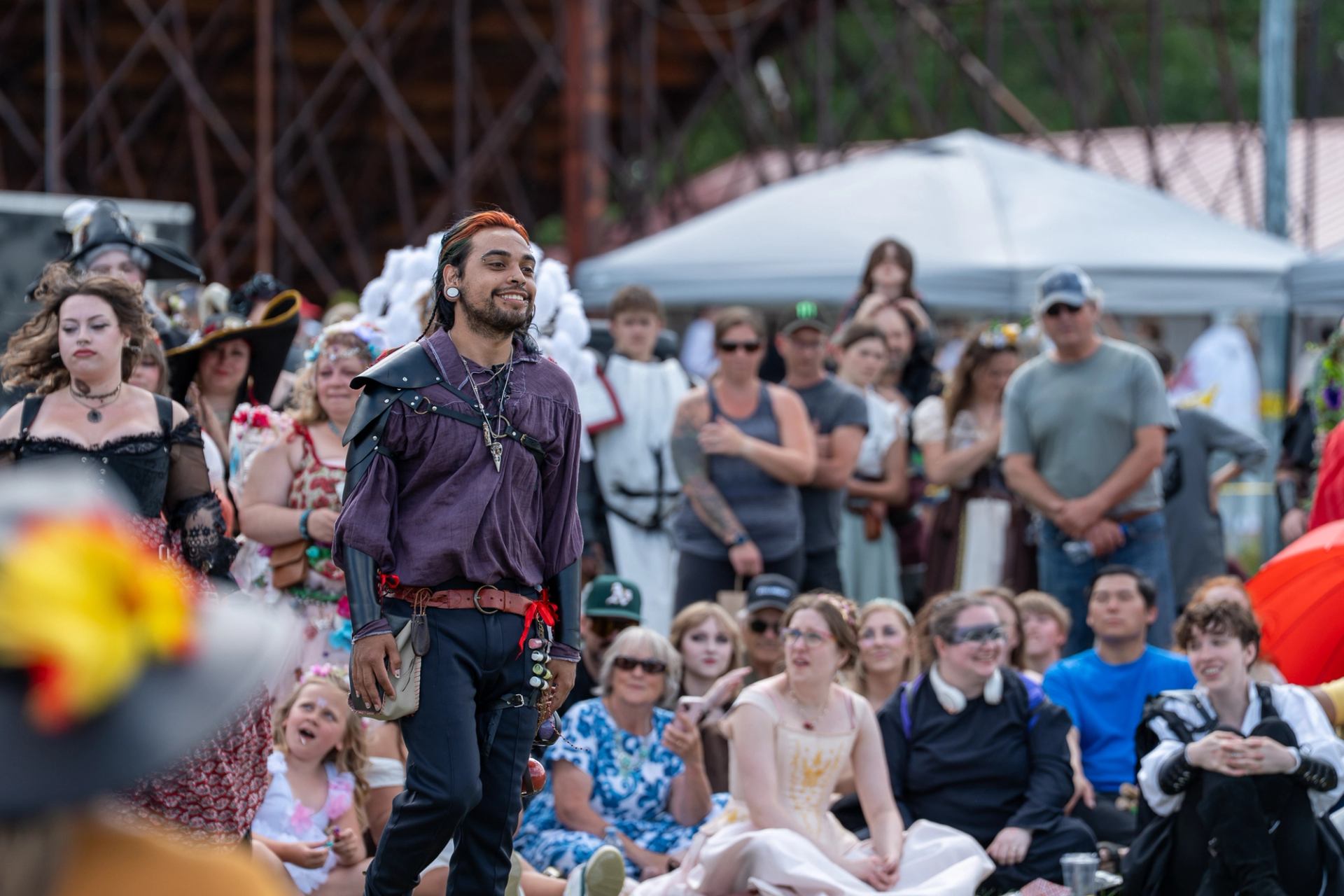 Costumed performer engaging an audience seated outdoors at a medieval-themed festival event.