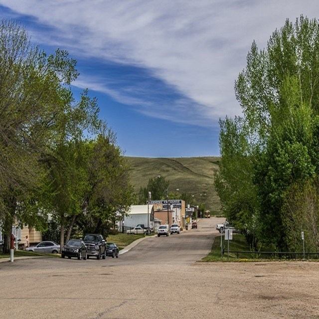Carbon East Campground entrance road with parked vehicles, trees and hills beyond.