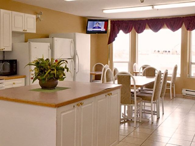 Kitchenette and dining area with white cabinets, large island, and multiple tables at Western Budget Motel.