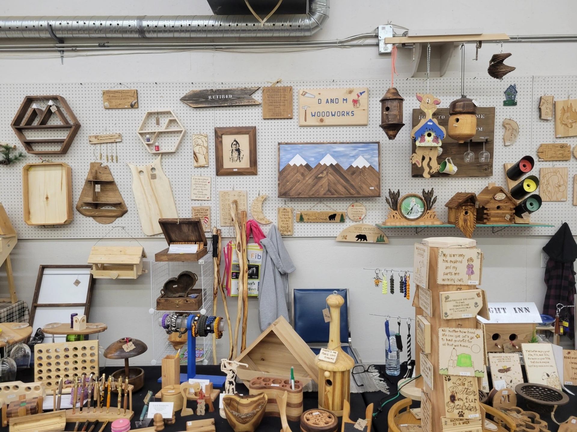 Display of handmade wooden decor, carvings, and crafts arranged on shelves and a market table.