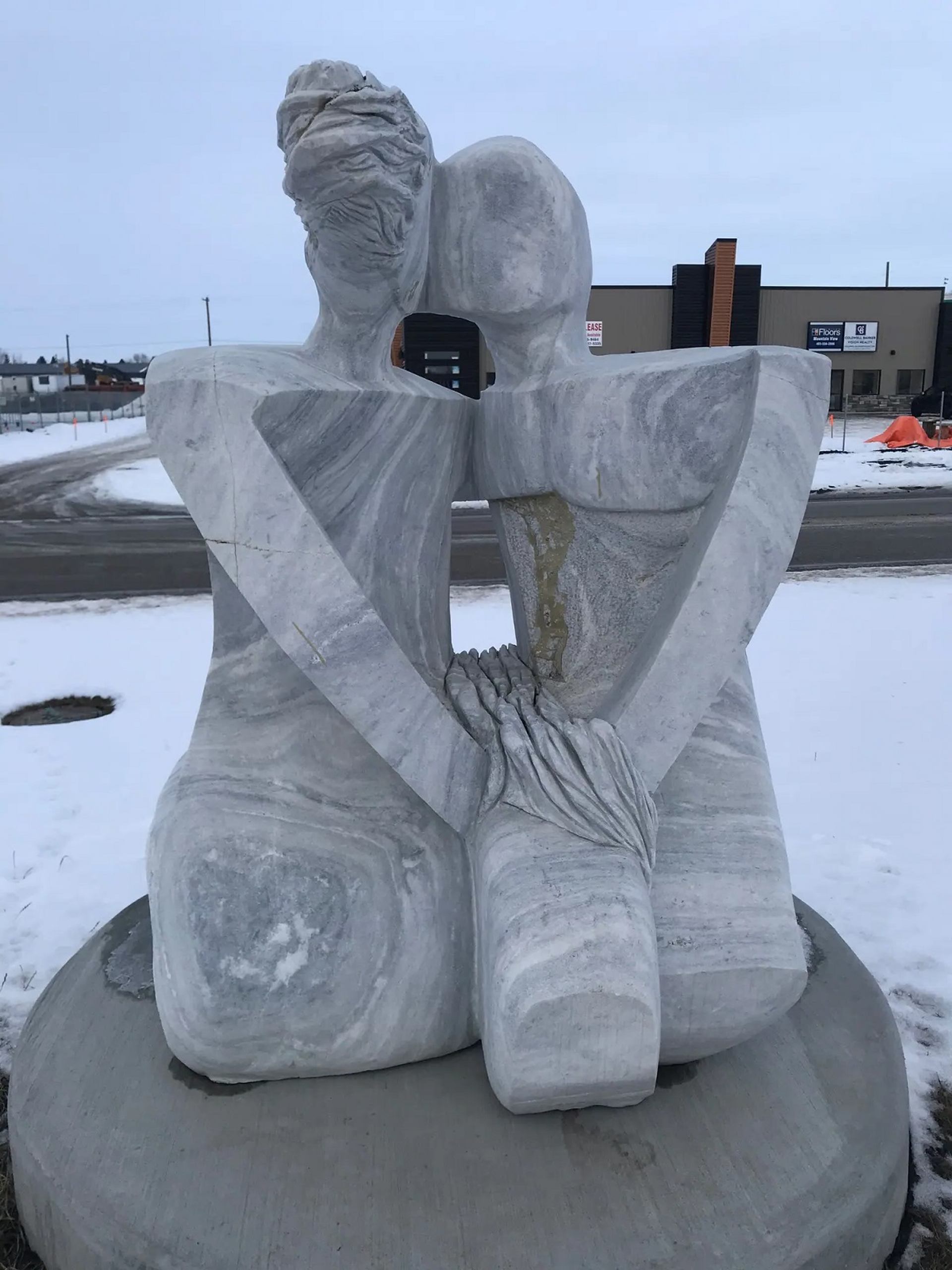 Stone sculpture depicts a couple sharing a kiss.