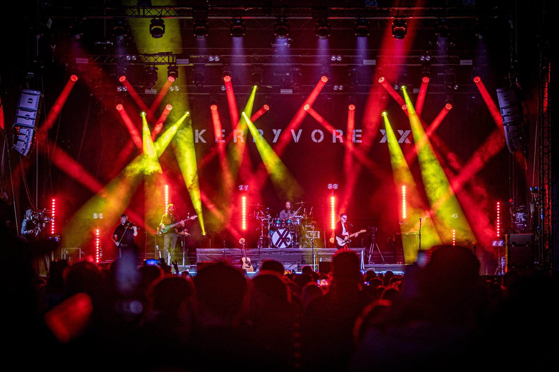 Concert stage with Skerryvore band performing under red and yellow lights before crowd.