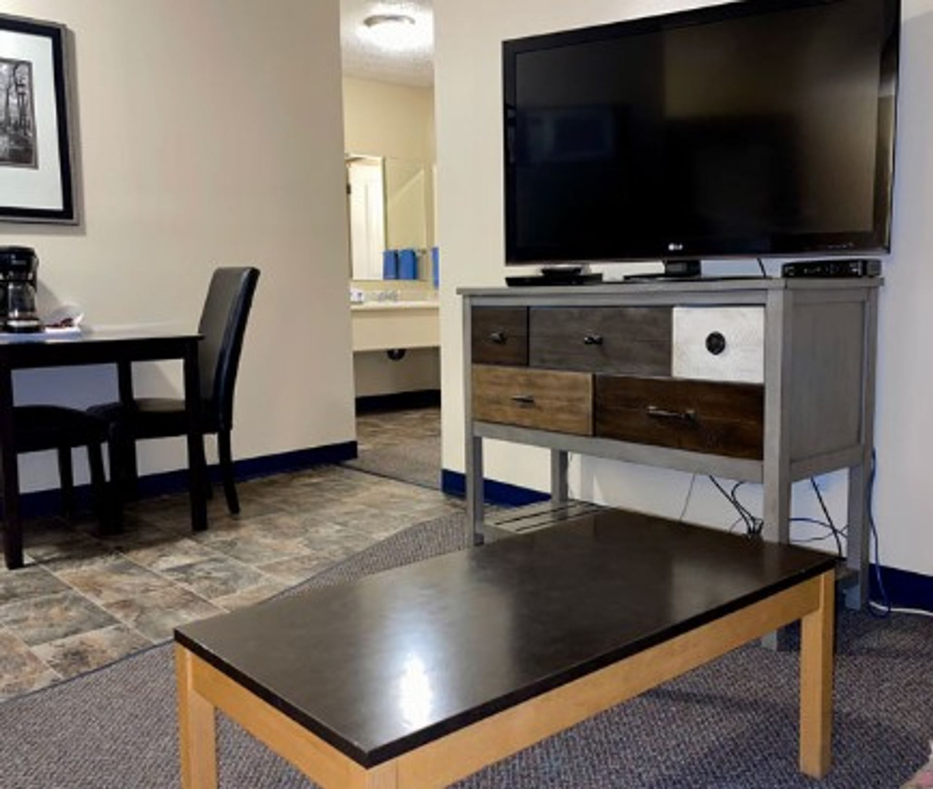 Guest room living area with flat-screen TV, coffee table, and workspace.
