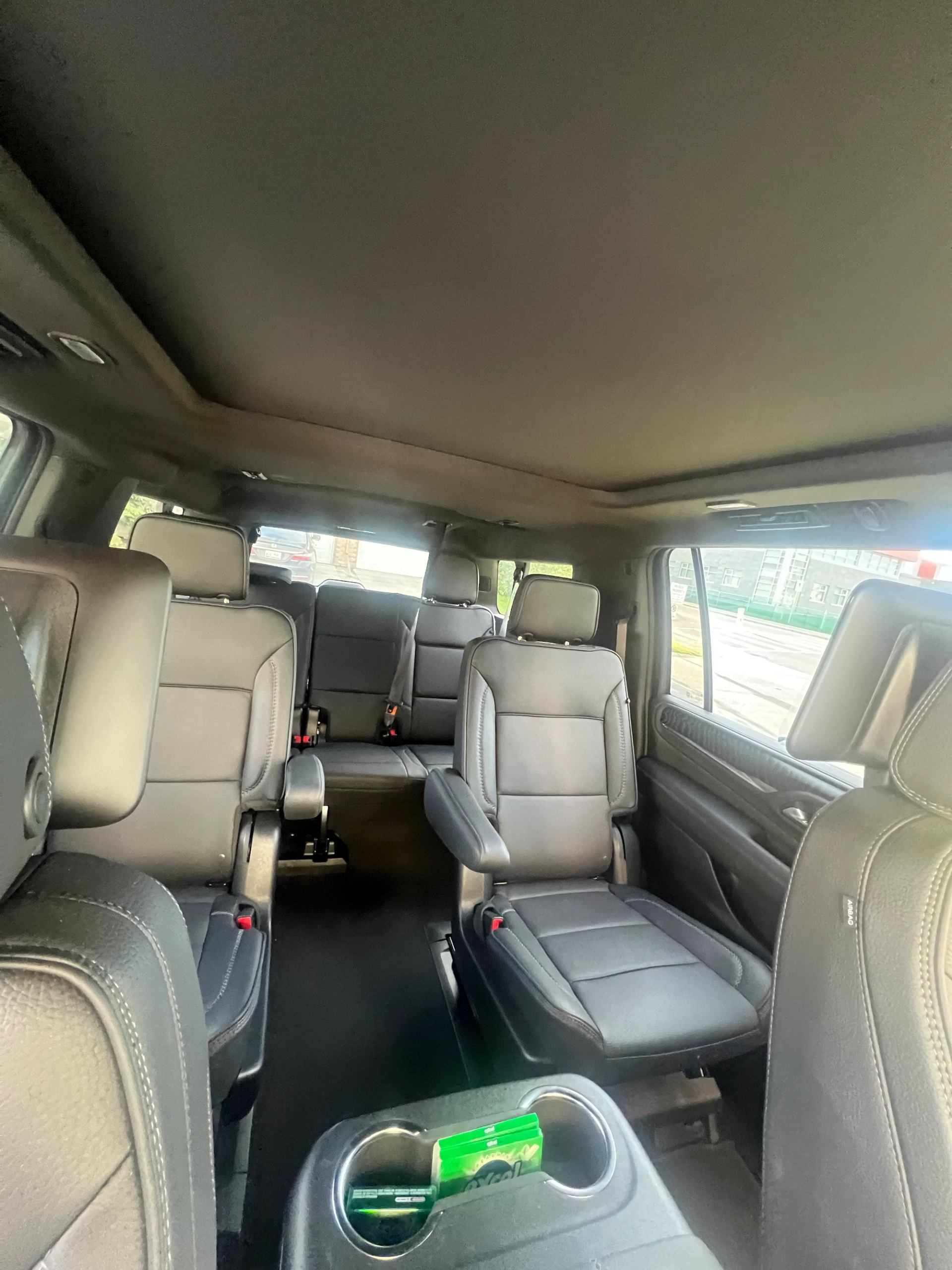 Interior of a minivan with three rows of black leather seats and console.