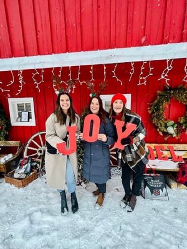 Three women hold large letter that spell JOY.