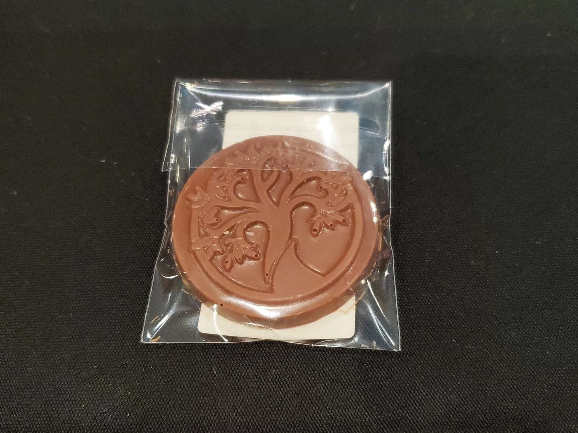 Embossed chocolate coin in clear wrapper with bird design.