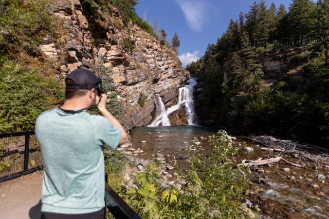 A man takes a photo of Cameron Falls.