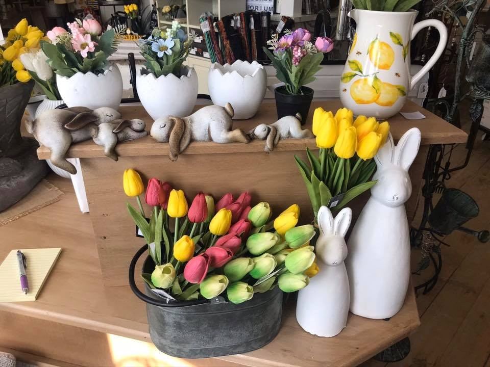 Gift shop shelf display with tulip flowers, ceramic rabbits, and a fruit-patterned mug.