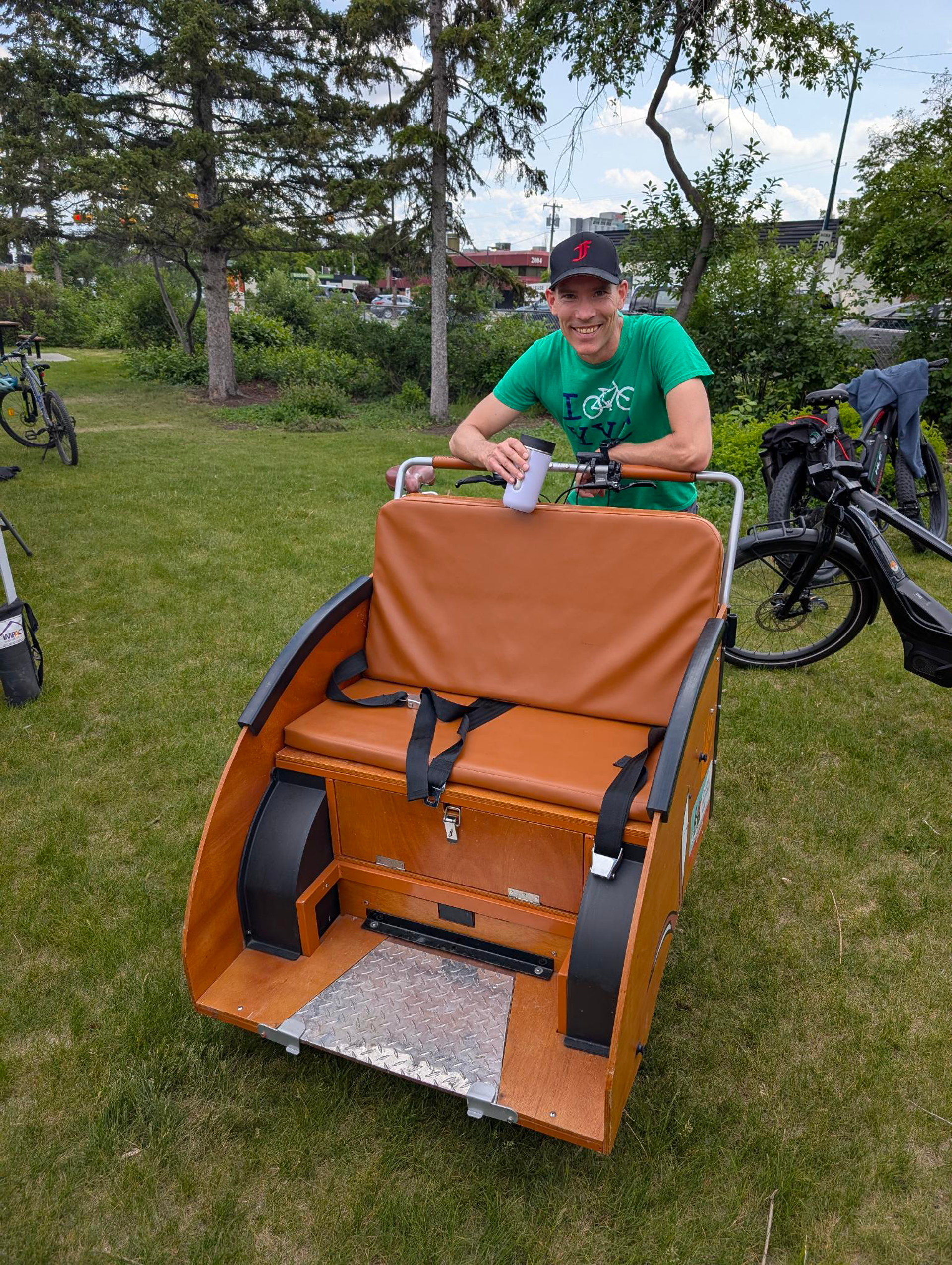 A person sitting on the Trixi Bike surrounded by grass and trees.