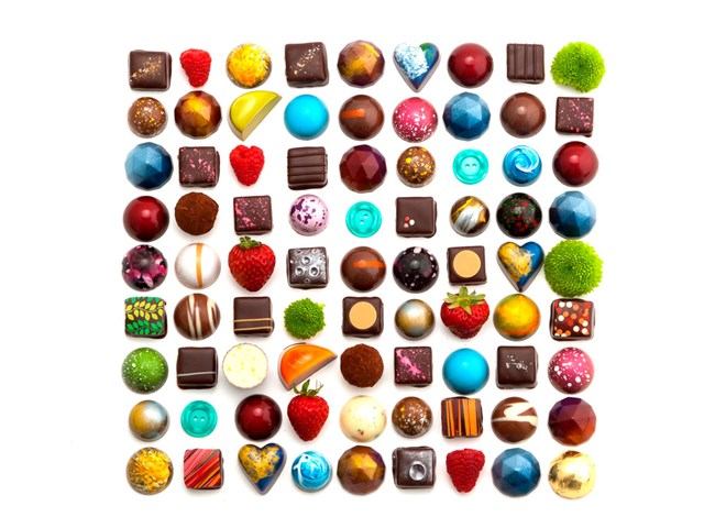 Assorted chocolate candies and truffles on a white background, including swirled and spherical shape.