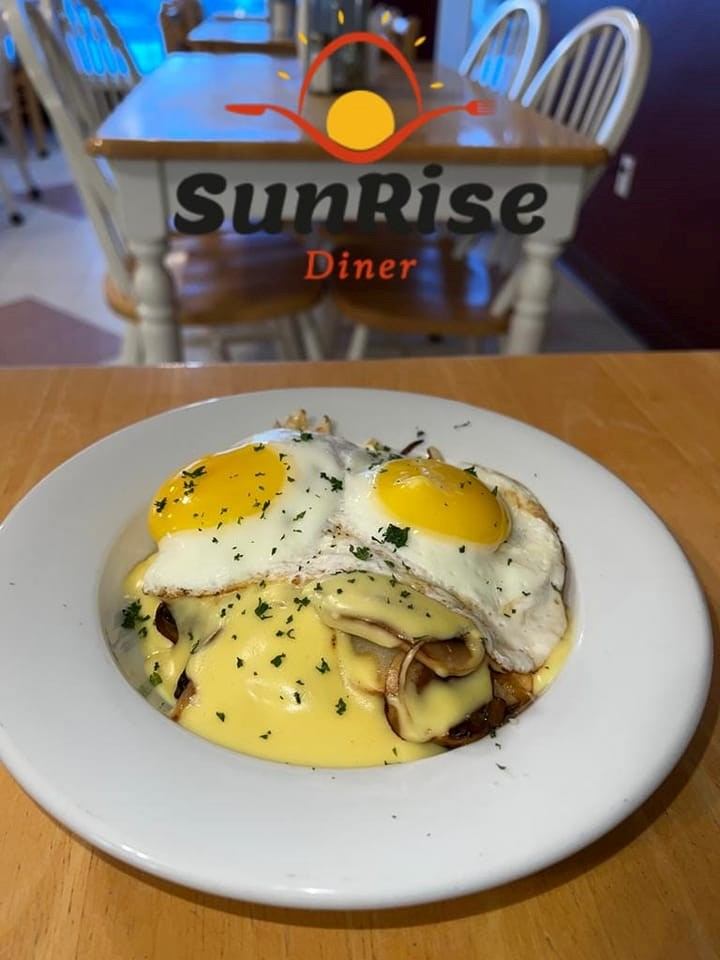 SunRise Diner sign and plated eggs benedict with hollandaise and herbs on a table.
