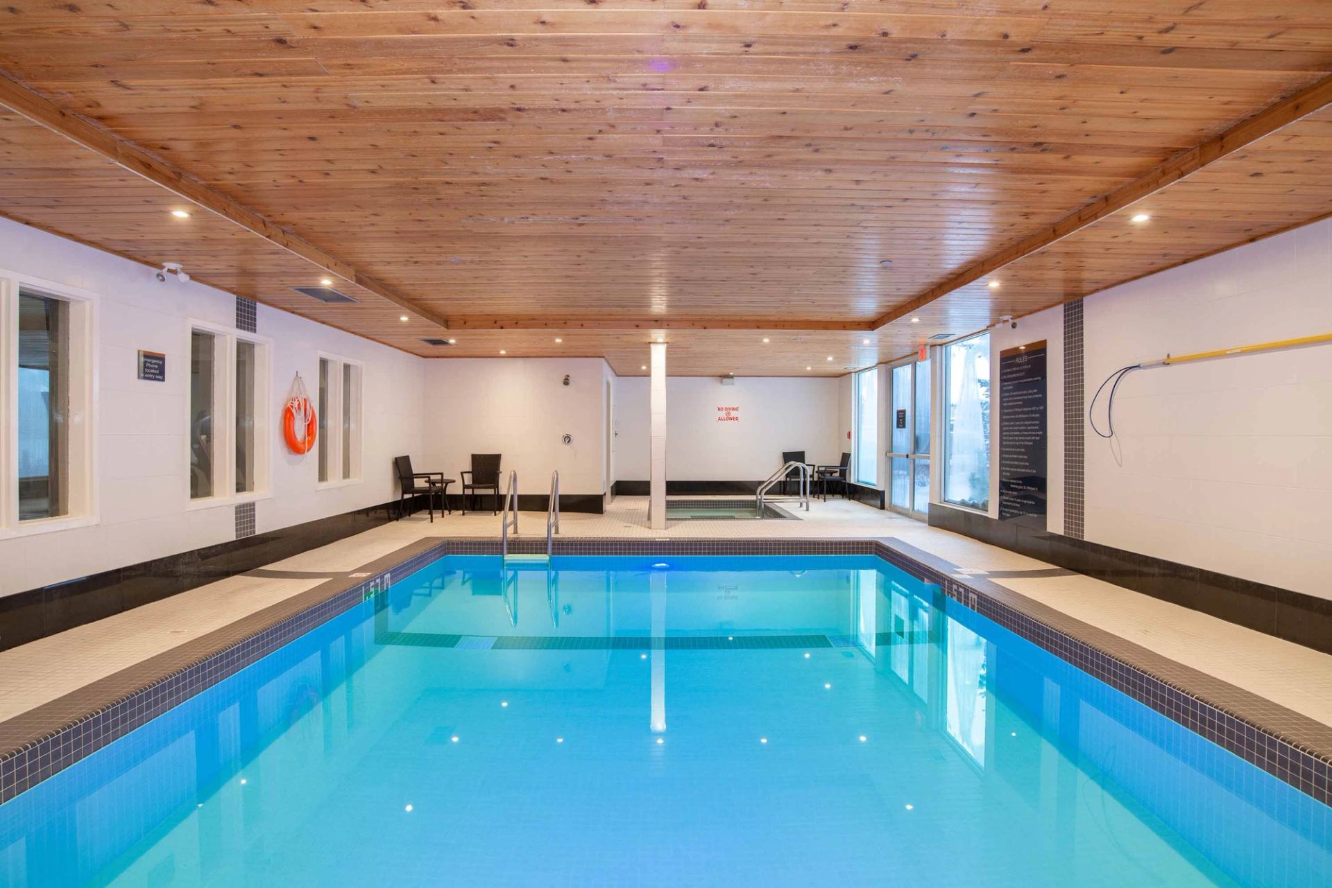Indoor swimming pool with hot tub, lounge chairs and wood-panelled ceiling.