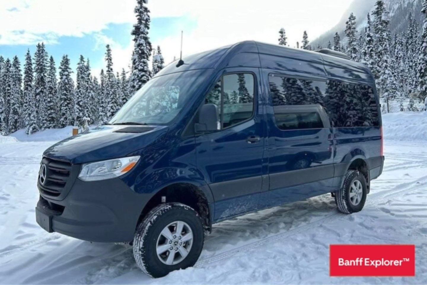 Blue Banff Explorer sprinter van parked in a snowy forest area