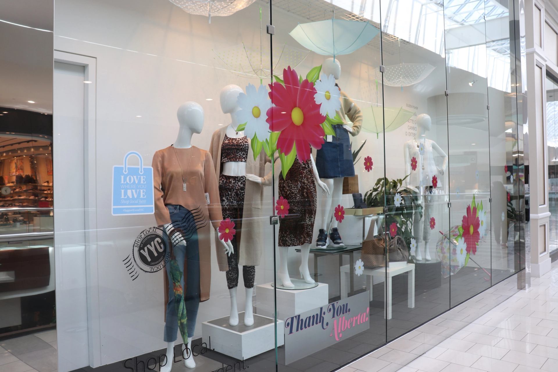 Mall storefront with mannequins, floral decals, and “Thank you” signage.
