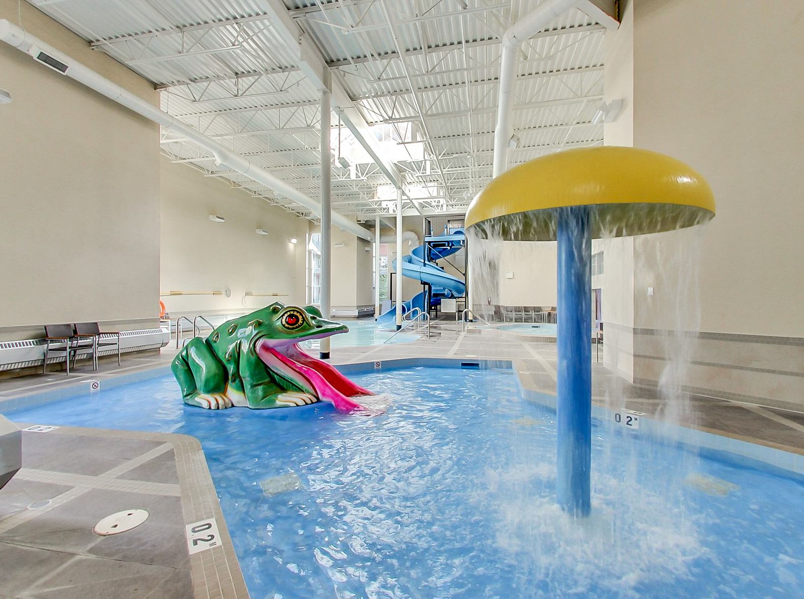 Indoor wading pool with frog slide, mushroom fountain and blue waterslide.