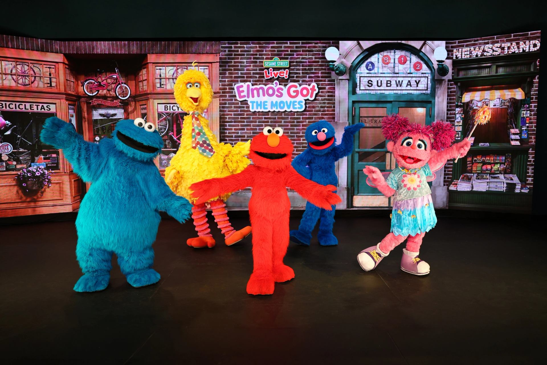 Sesame Street characters pose onstage before Elmo’s Got the Moves backdrop.