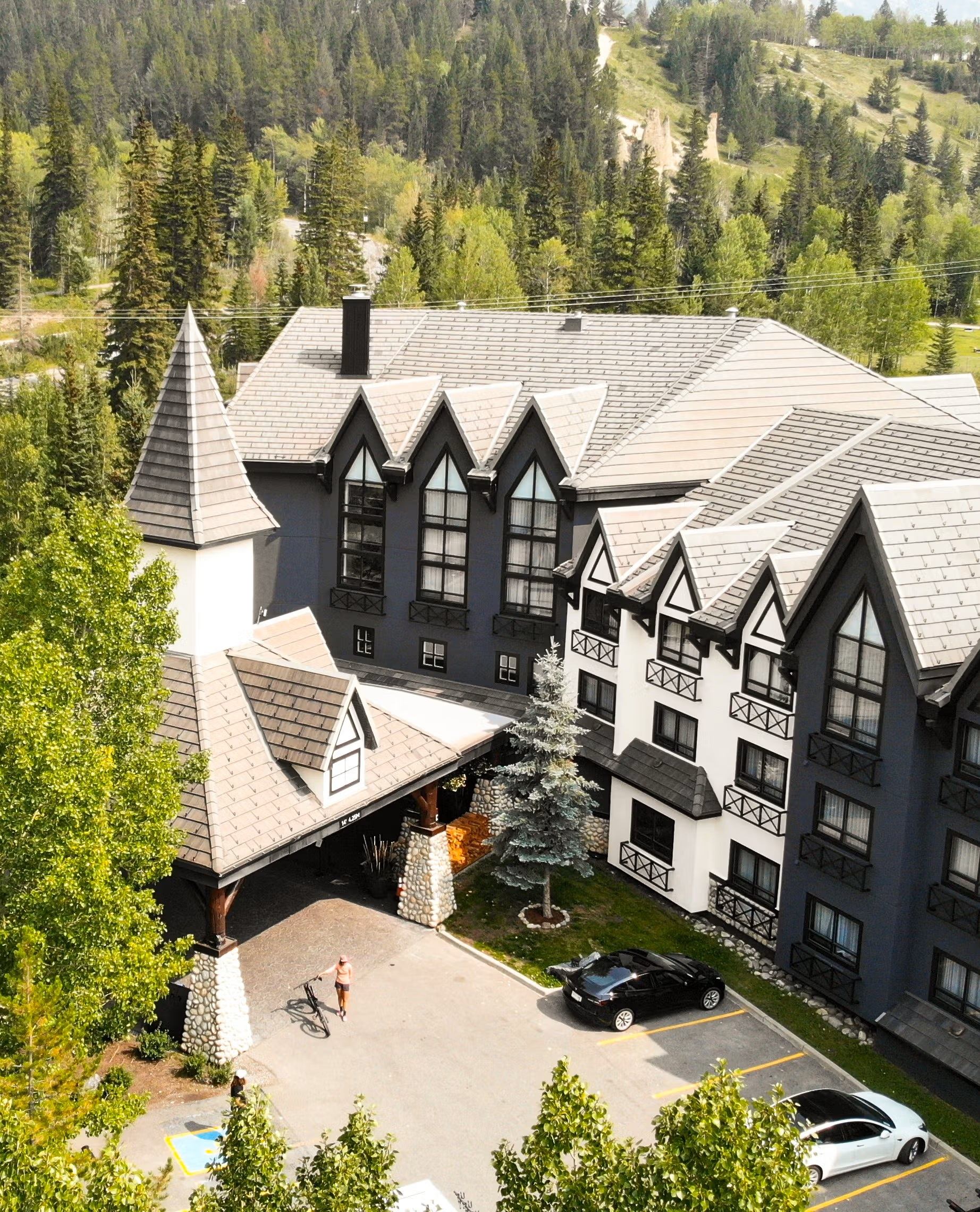 Exterior view of Everwild Hotel with peaked roofs, stone details, and trees set against a hillside.