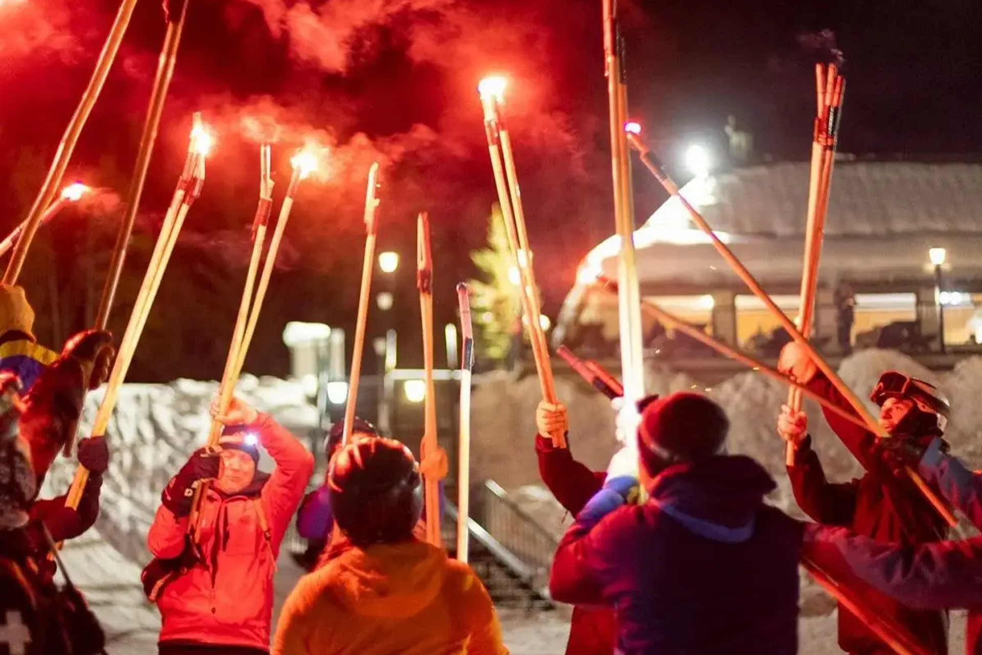 Group holding glowing red torches outdoors during Norquay’s New Year celebration.