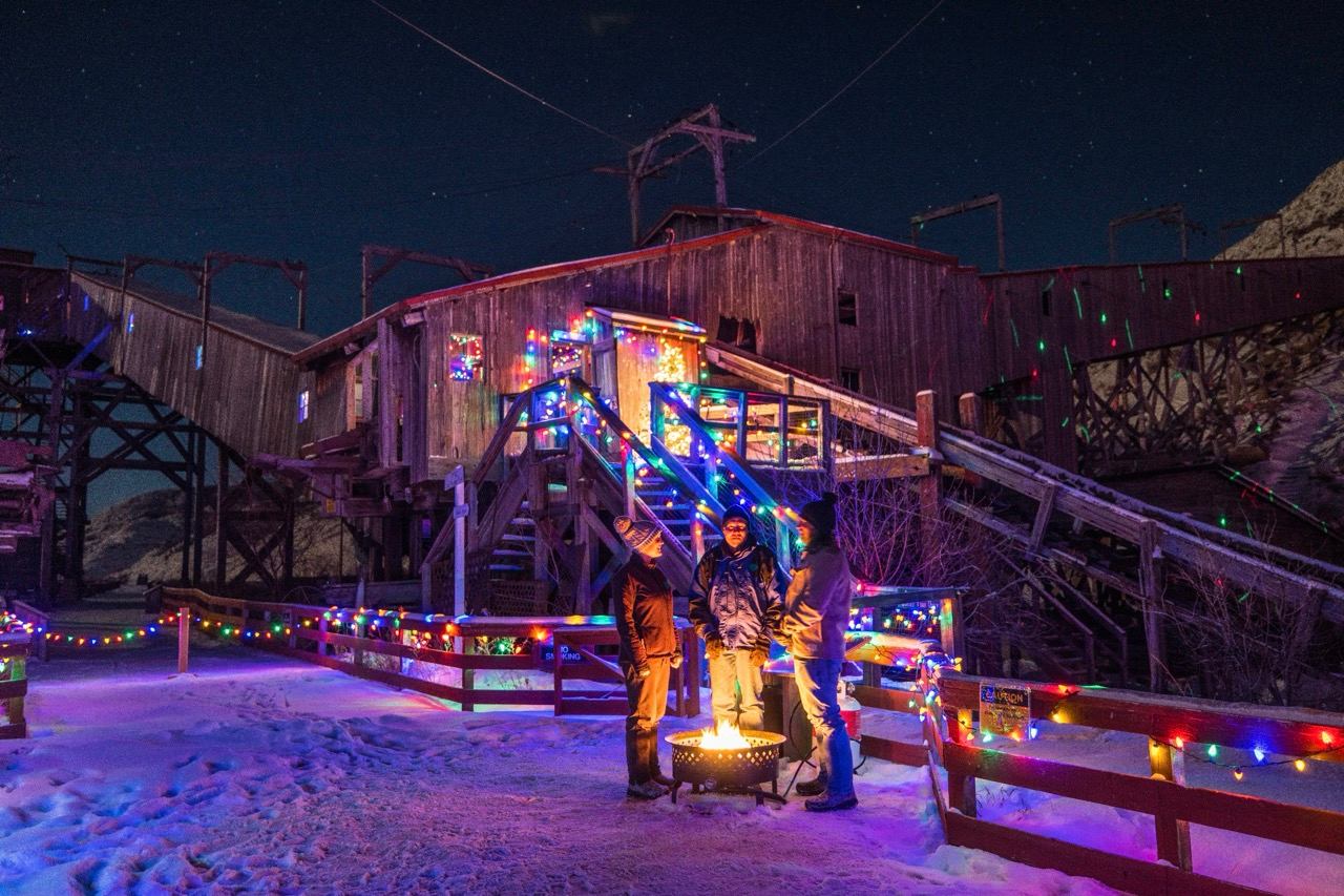 People stood around a fire, surrounded by colourful lights