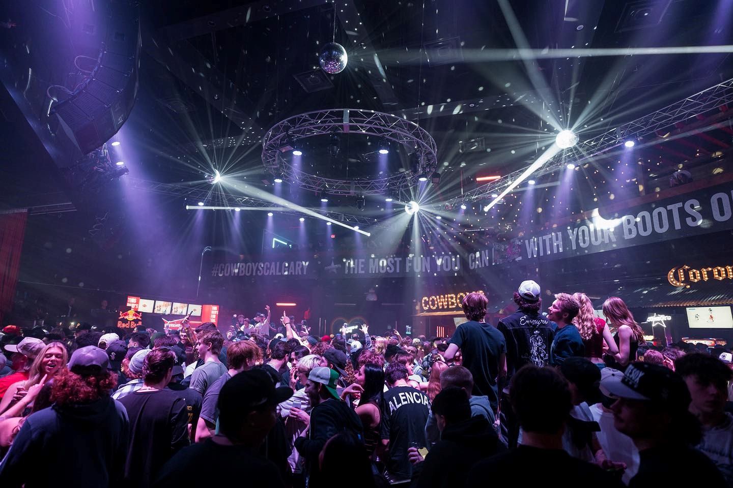 Crowded venue with stage lights and vibrant nightlife at Cowboys Dance Hall.