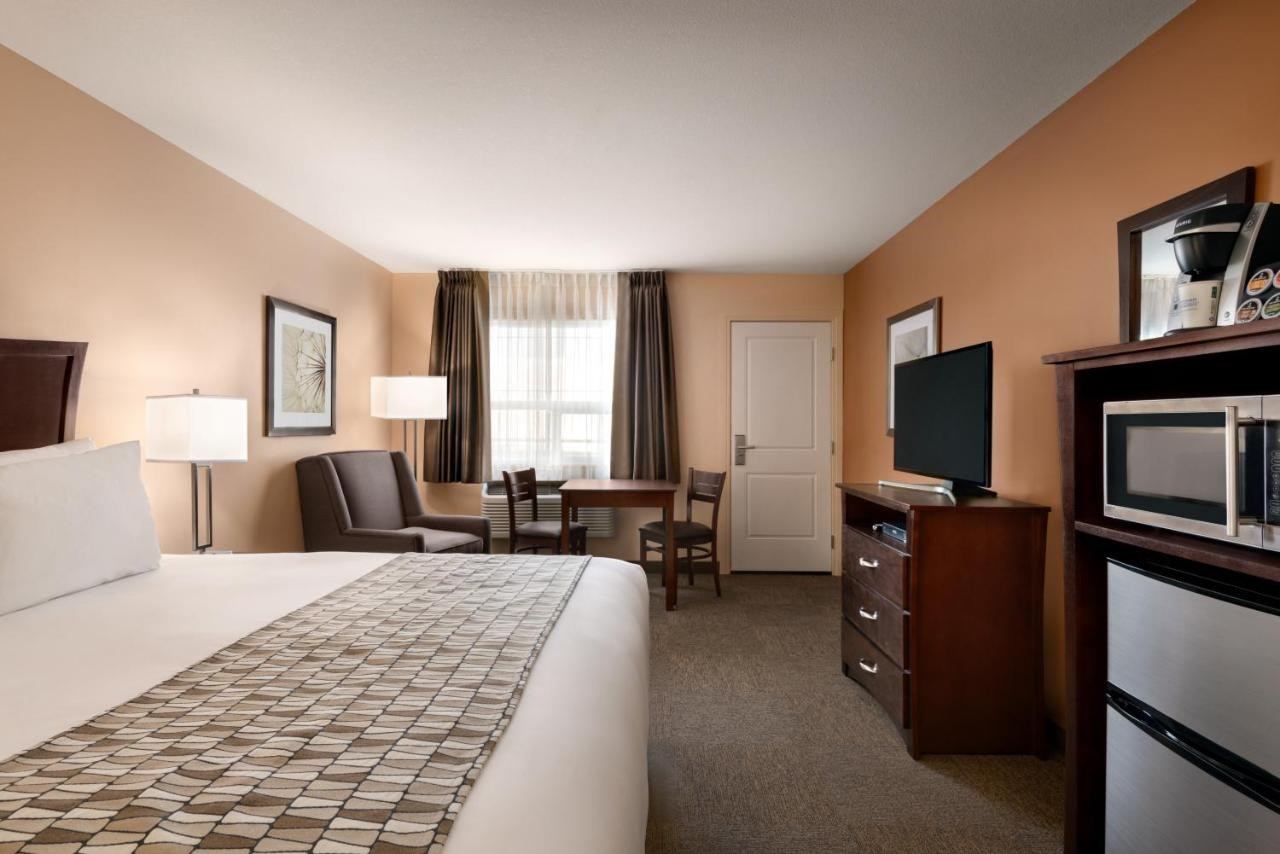 Travelodge room with king bed, TV, microwave, and seating area.