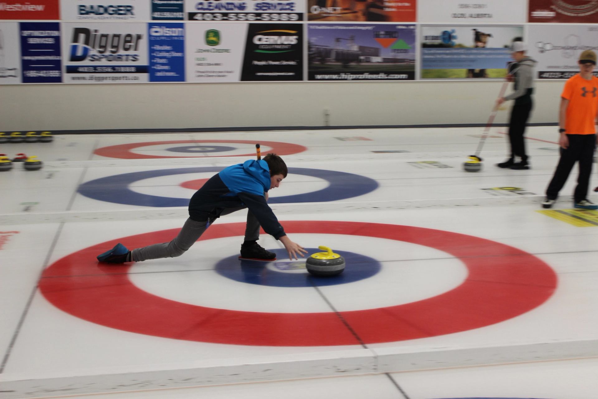 Curler slides yellow stone toward house.