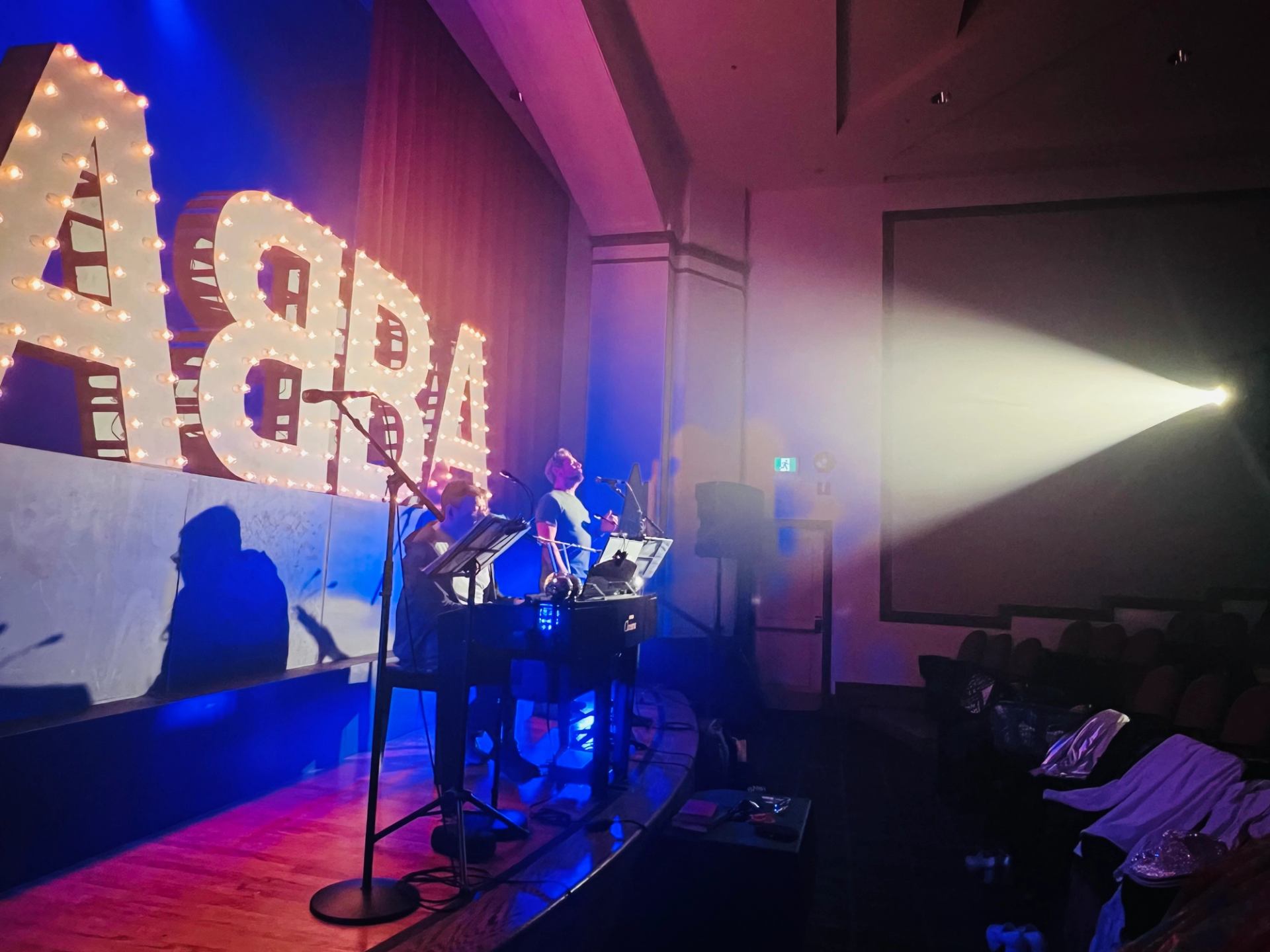ABBA-themed stage with performers under bright spotlight.