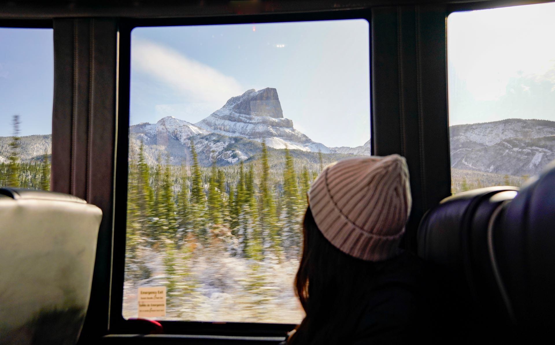 A woman sat on the bus looking out the window at the mountains.