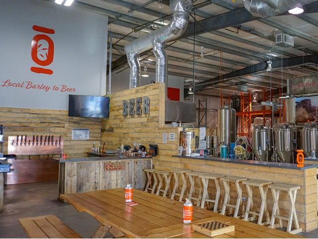 Origin Taproom bar with wooden benches and up to 12 beers on tap, featuring a rustic and inviting setup.