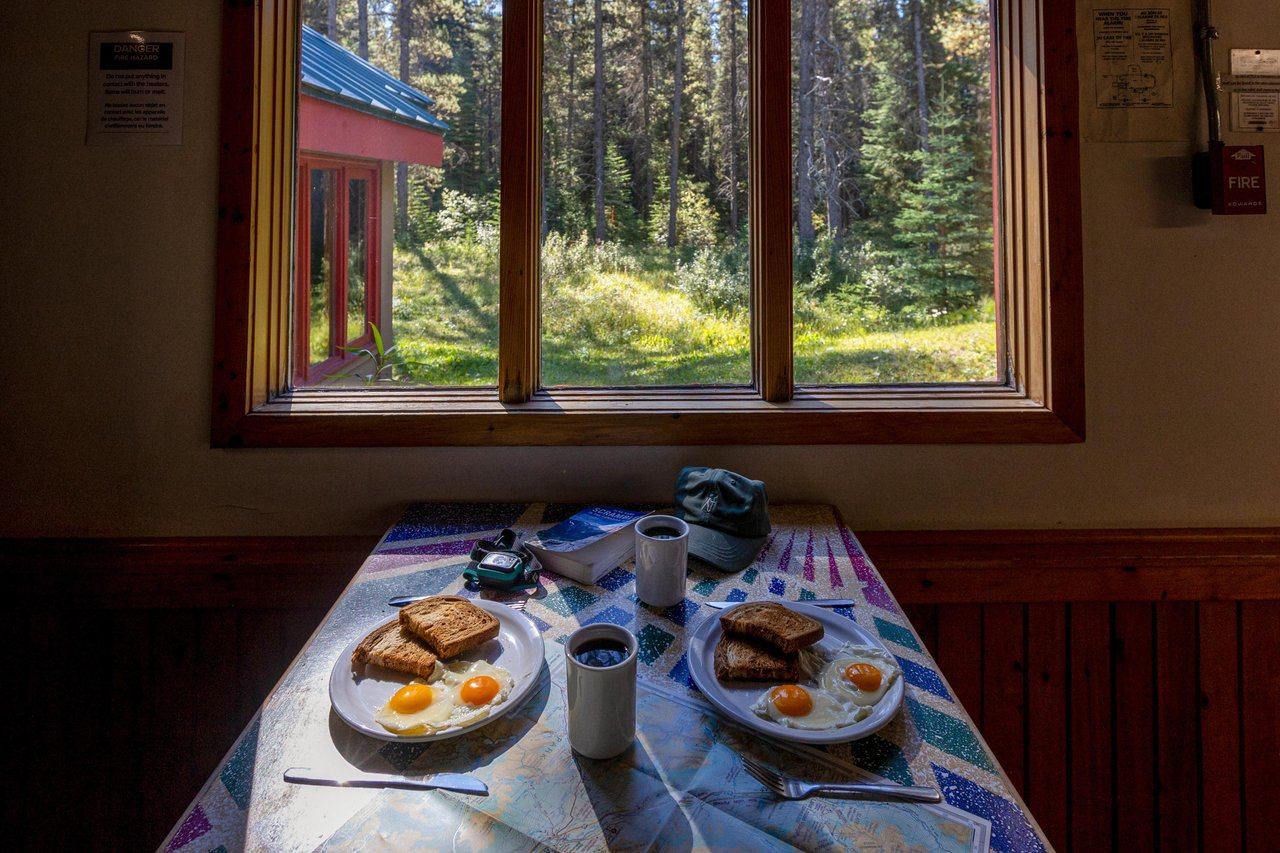 Eggs and toast with coffee on a table by the window with forest views.