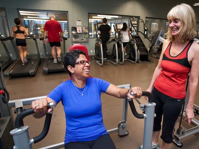 Two women talking while they utilize the fitness centre at Elevation Place.