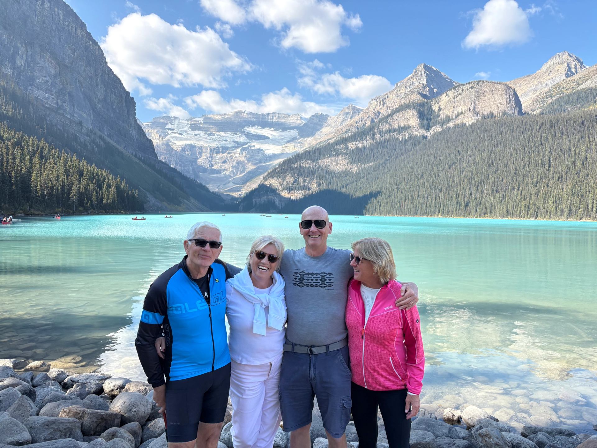 Tour guests posing together at Lake Louise with mountains and turquoise water.