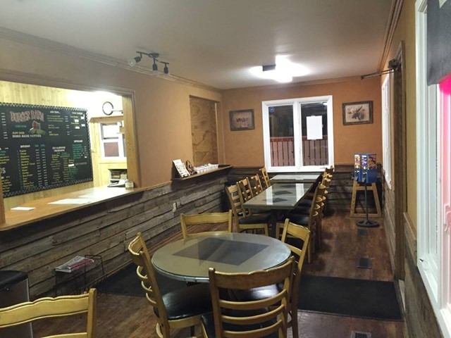 Cozy Burger Barn interior with wooden tables, counter, and menu board.