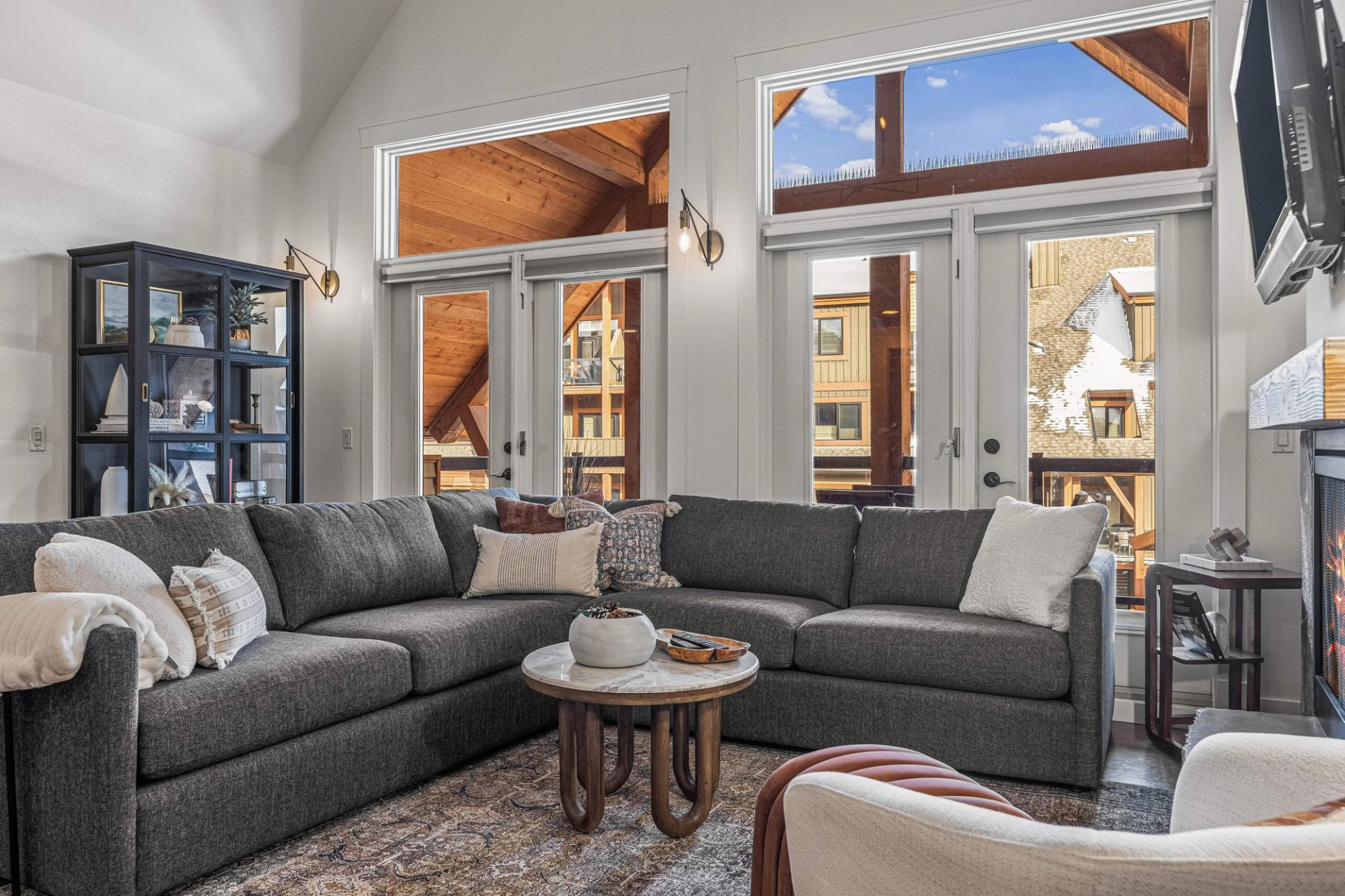 Living room with grey sectional sofa, round coffee table and large windowed doors.