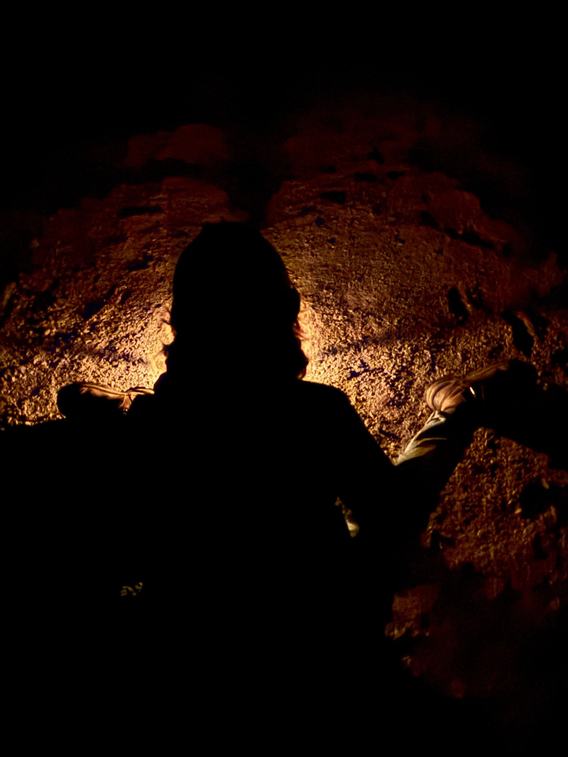 Silhouette against a glowing orange rock wall deep inside Bellevue Underground Mine.