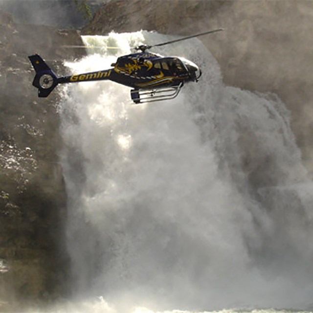 a helicopter flying past a canyon falls