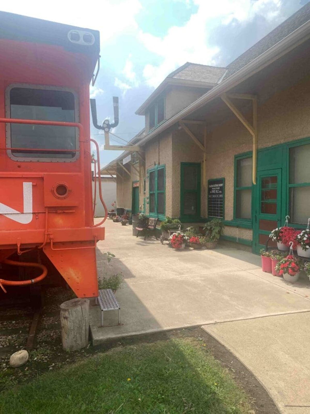 Historic train station courtyard with orange railcar and potted red flowers.