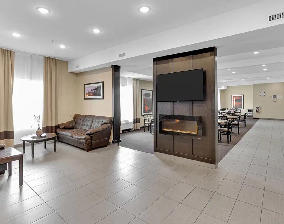 Modern hotel lobby with leather seating, fireplace, and dining area.