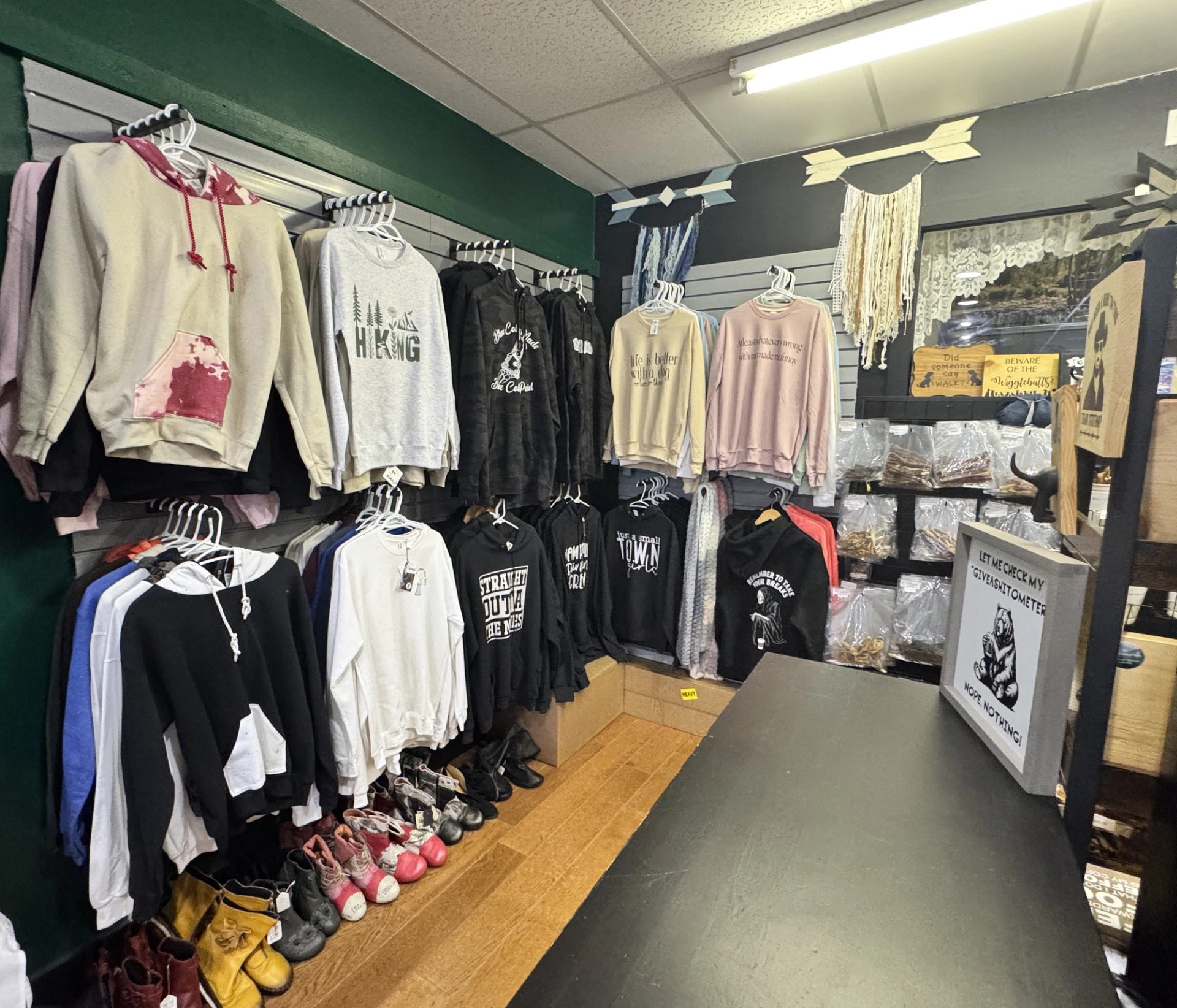 Wall display of sweaters, hoodies, footwear, and accessories in a boutique retail space.
