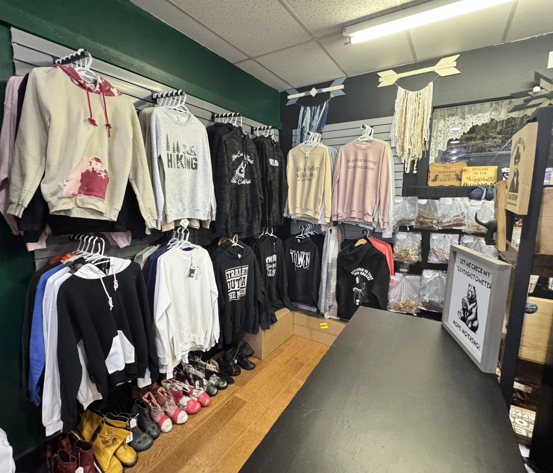 Wall display of sweaters, hoodies, footwear, and accessories in a boutique retail space.