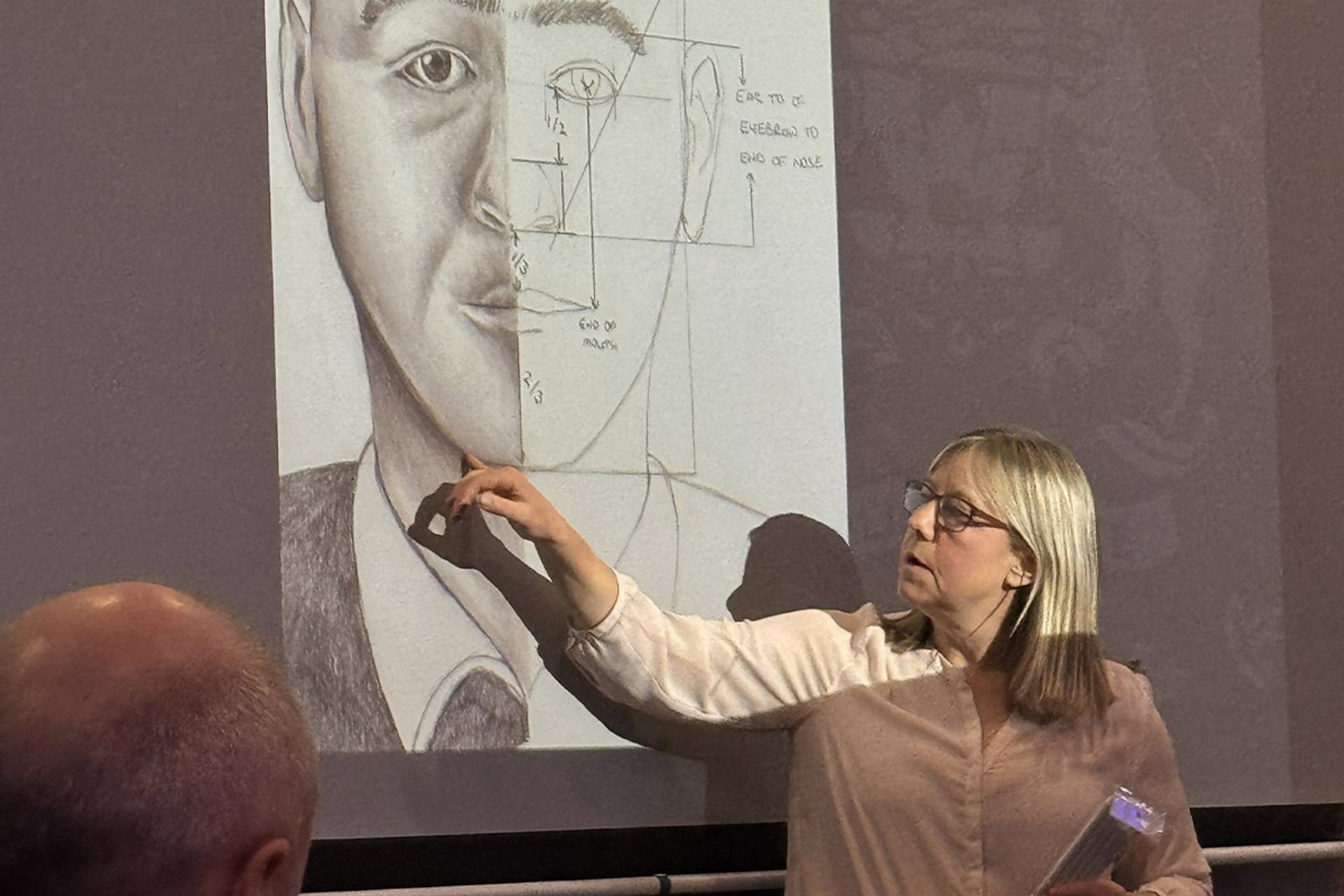Person sketching on a large paper during a true crime-themed Sip & Sketch event.