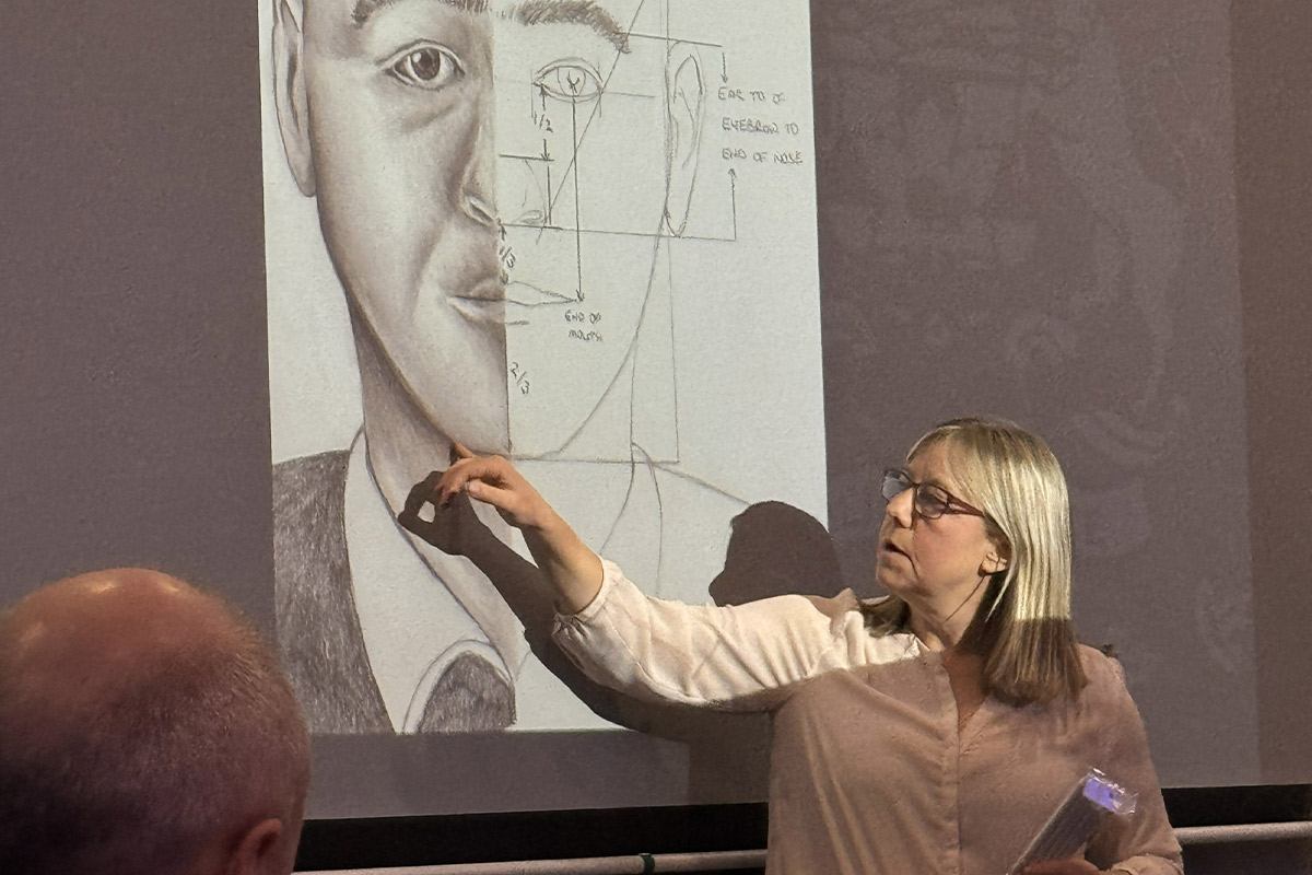 Person sketching on a large paper during a true crime-themed Sip & Sketch event.