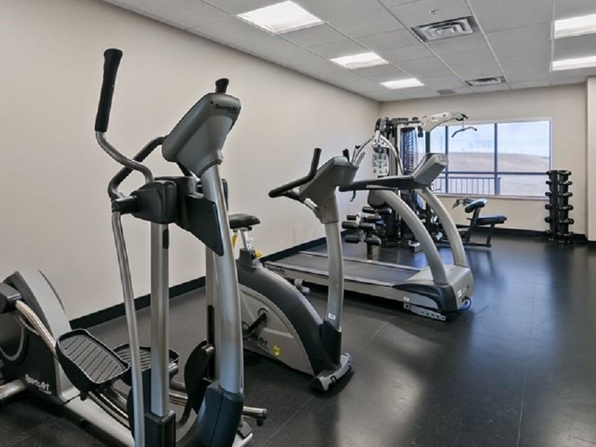 Hotel fitness center featuring treadmills, elliptical machines, and weight rack