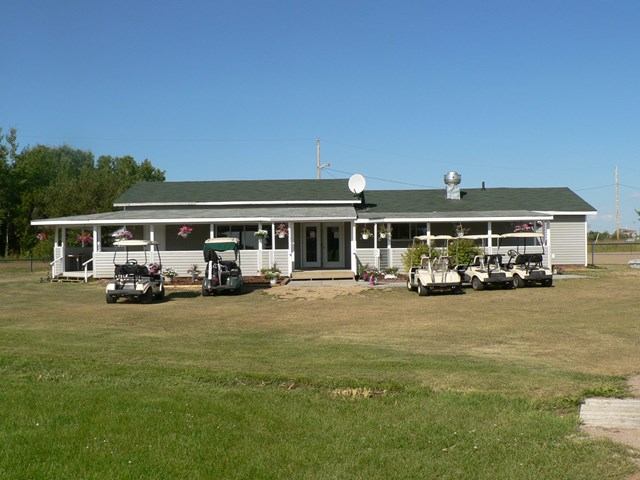 Clubhouse at Smoky River Golf Course with golf carts and green roof.